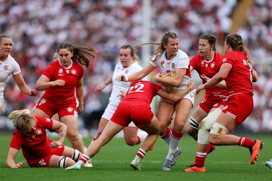 An England ball-carrier is tackled by Canada defenders during the Women's Rugby World Cup 2025 final in London
