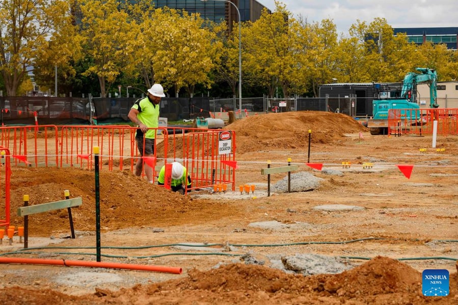Workers in high-visibility clothing at an excavation site in Canberra with an excavator in the background