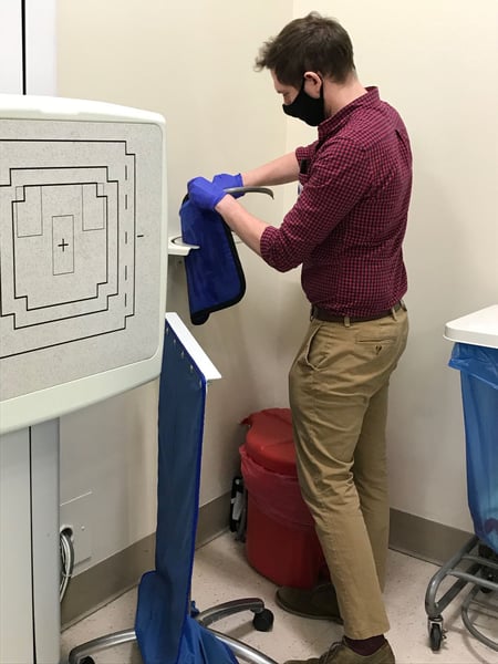 Epidemic Intelligence Service officer in a mask and gloves swabbing surfaces in a Connecticut hospital room to test for Candida auris