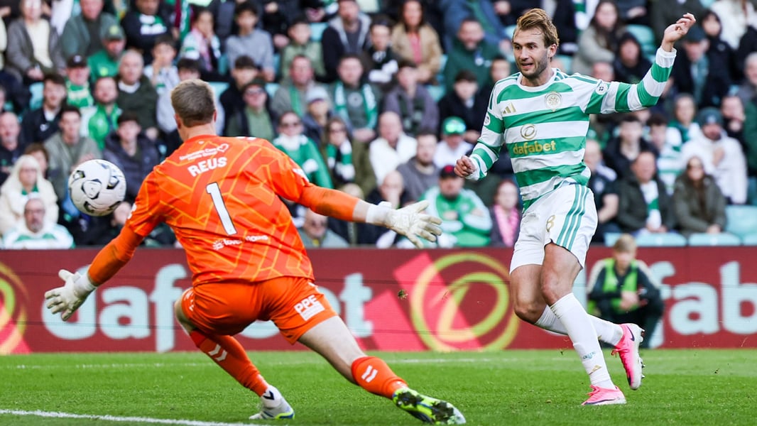 A Celtic attacker in green and white hoops shoots past Hearts goalkeeper Reus during the Scottish Premiership match at Celtic Park