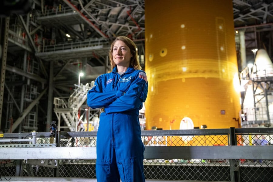 NASA astronaut Christina Koch standing in front of a Space Launch System rocket stage inside the Vehicle Assembly Building
