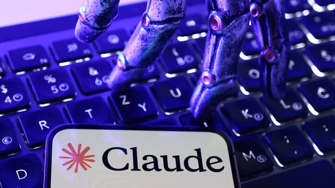 Illustration of a robotic hand over a keyboard with the Claude logo on a phone screen