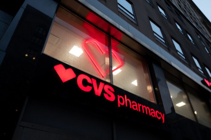 Illuminated red CVS Pharmacy sign on a building in New York City at dusk