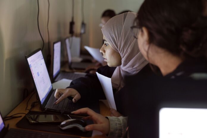 Young women working at laptops in a skills class in Damascus, Syria
