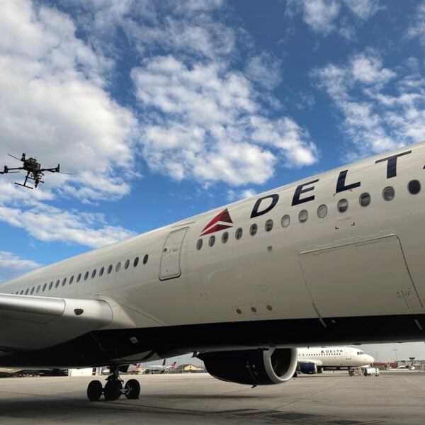 An autonomous drone hovers beside the fuselage of a Delta Air Lines Airbus A350-900 parked on an airport ramp