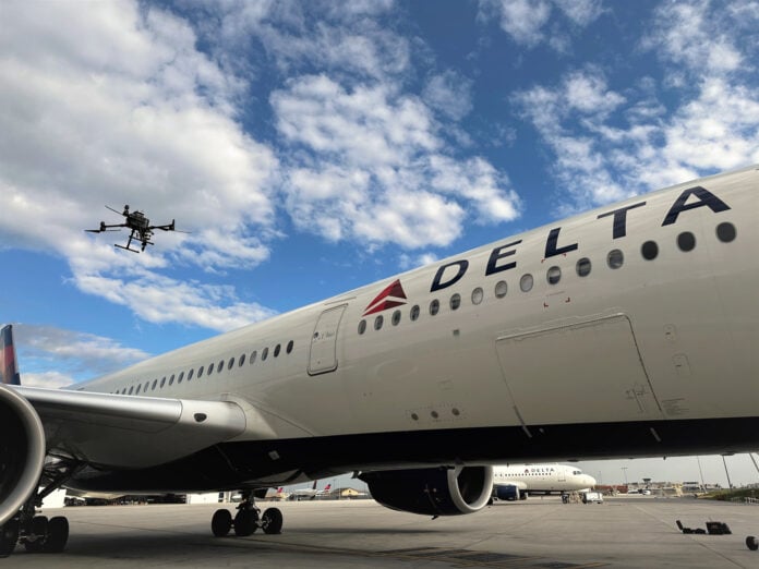 An autonomous drone hovers beside the fuselage of a Delta Air Lines Airbus A350-900 parked on an airport ramp