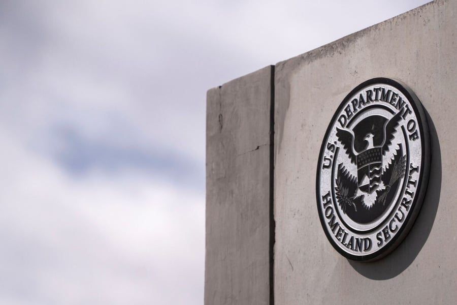 The Department of Homeland Security seal mounted on a concrete wall against a cloudy sky