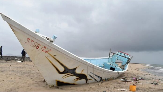 A wrecked wooden boat lies on a beach under a stormy sky after a migrant shipwreck off Djibouti