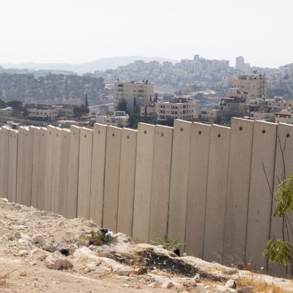 Concrete separation wall with Palestinian and Israeli housing blocks behind it east of Jerusalem, near the planned E1 settlement site