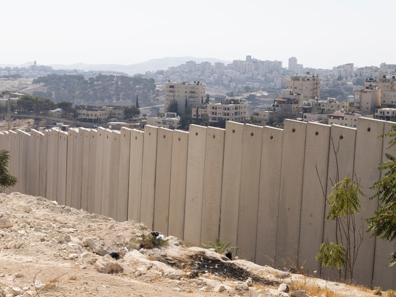 Concrete separation wall with Palestinian and Israeli housing blocks behind it east of Jerusalem, near the planned E1 settlement site