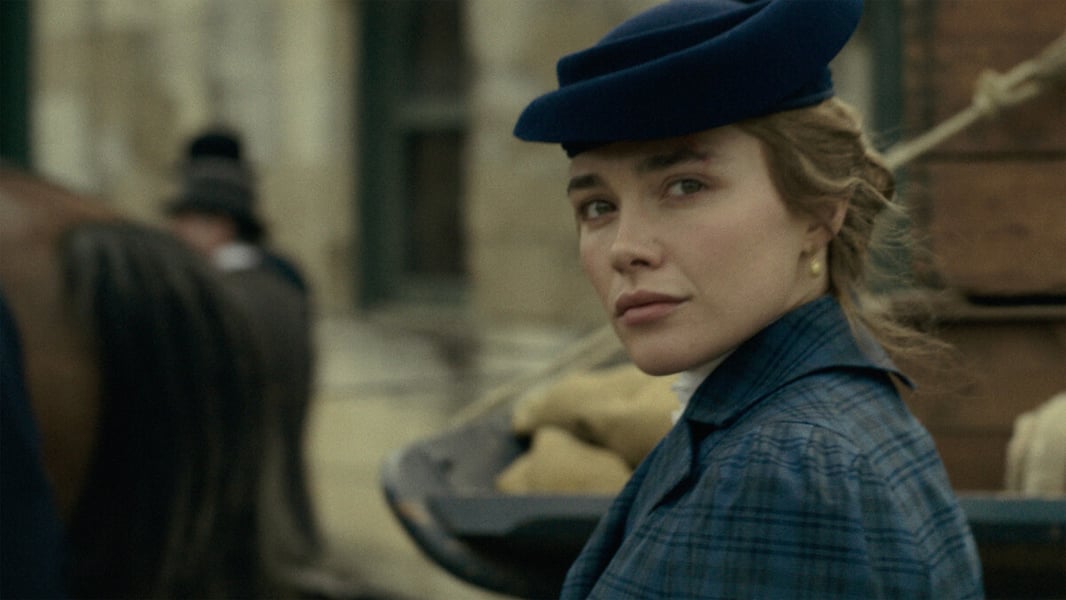 A woman in a blue plaid jacket and navy hat looks over her shoulder beside a horse and wagon in a promotional still from Netflix's East of Eden