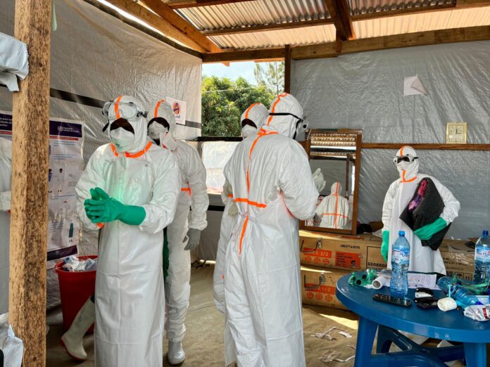 Health workers in white protective suits, goggles and masks prepare inside a tented Ebola treatment centre in Bunia, Ituri province
