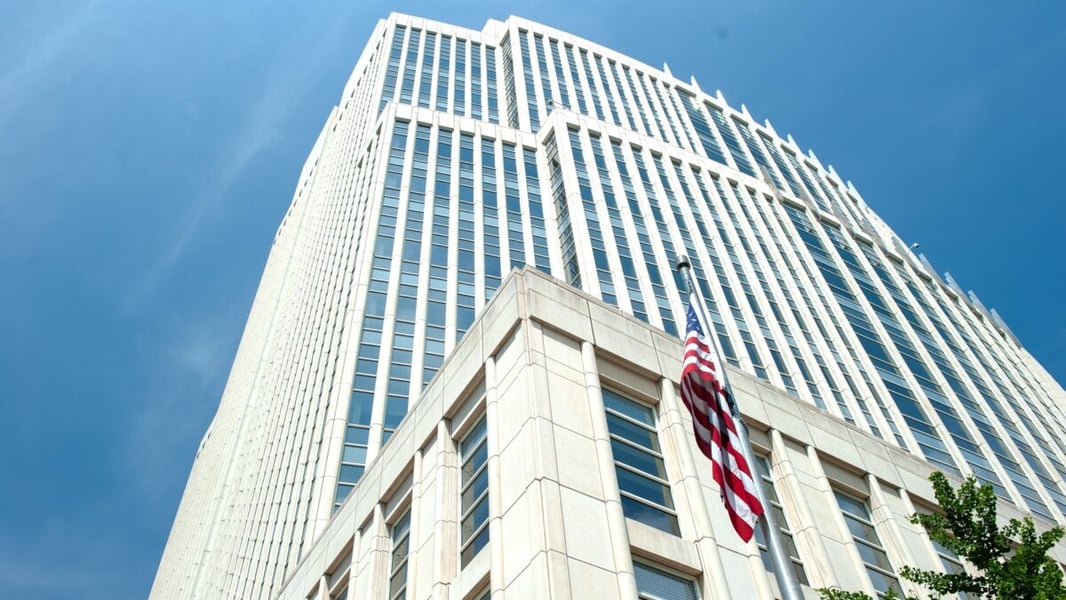 Tall glass and limestone federal courthouse tower with an American flag against a blue sky