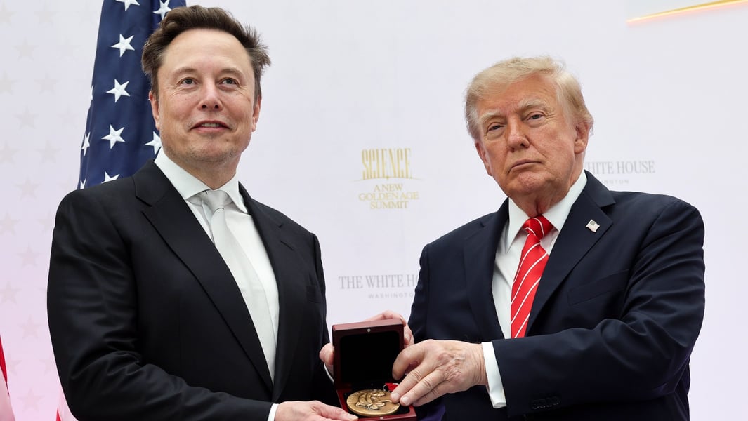 Elon Musk and President Donald Trump hold the National Medal of Science in a presentation box in front of a White House event backdrop