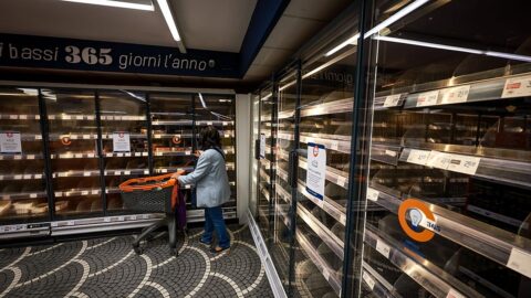 A woman looks at empty supermarket shelves in Naples, Italy, following truckers' protests over fuel prices