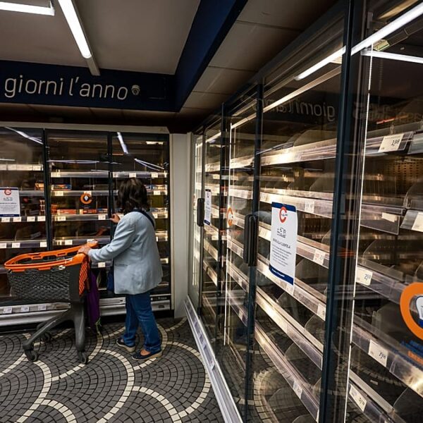 A woman looks at empty supermarket shelves in Naples, Italy, following truckers' protests over fuel prices