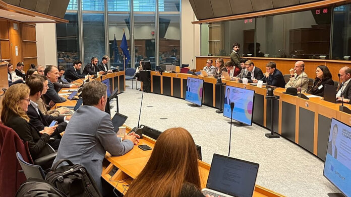 Officials and satellite industry representatives seated around a horizontal table at a satellite connectivity meeting in the European Parliament, 13 October 2026
