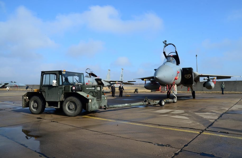 An F-15C Eagle being towed on the ramp at Siauliai Air Base, Lithuania, with other F-15Cs and airmen behind it, in a 2014 file photo