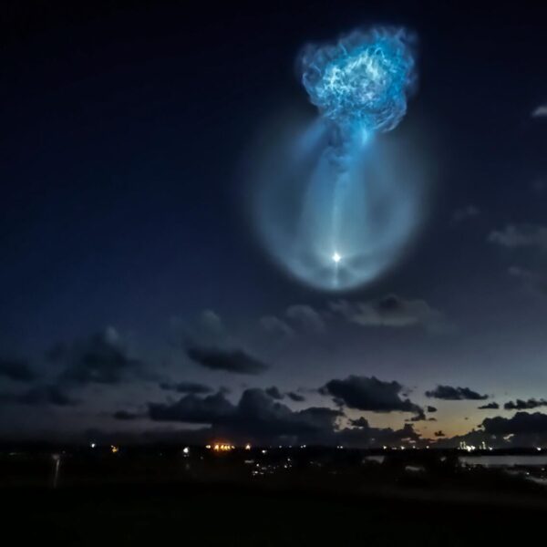 A glowing blue jellyfish-shaped exhaust plume from the Falcon 9 second stage in the pre-dawn sky over Florida