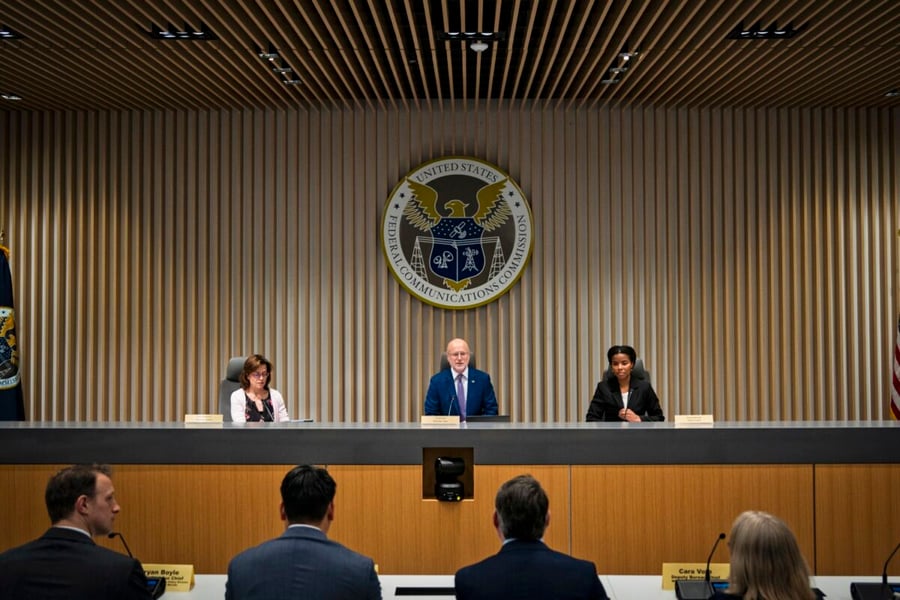 FCC Chairman Brendan Carr seated at the center of the commission dais beneath the agency seal