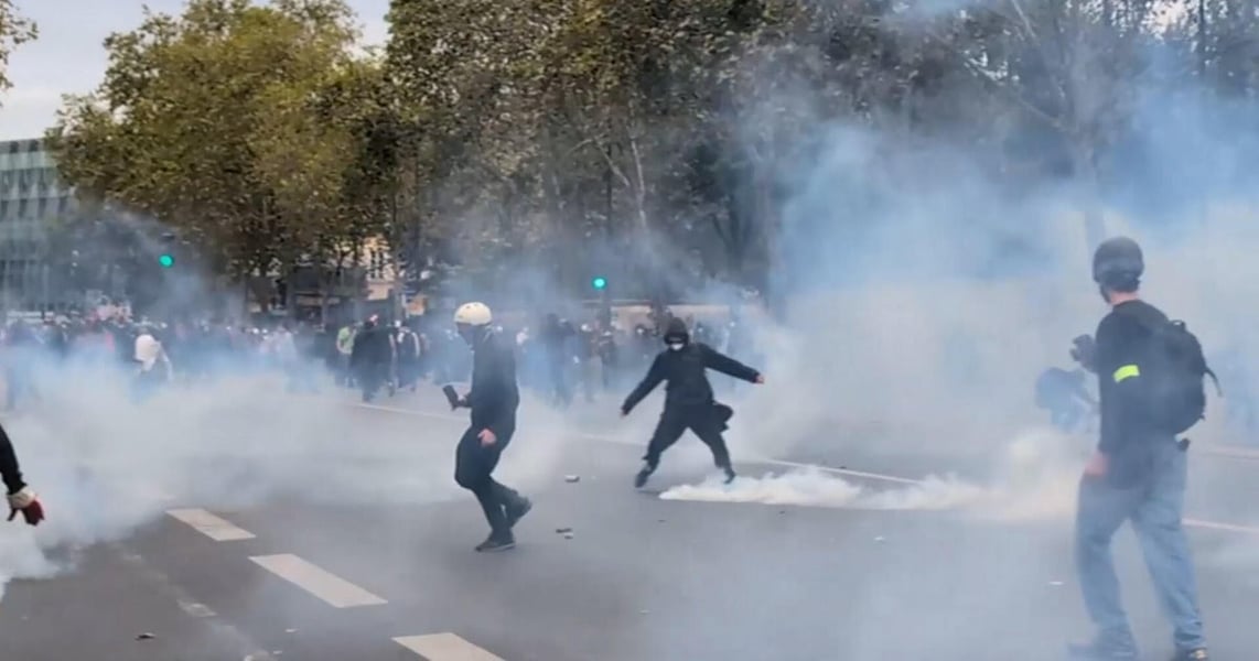 Masked protesters in clouds of tear gas on a French street during a clash with police at a student protest