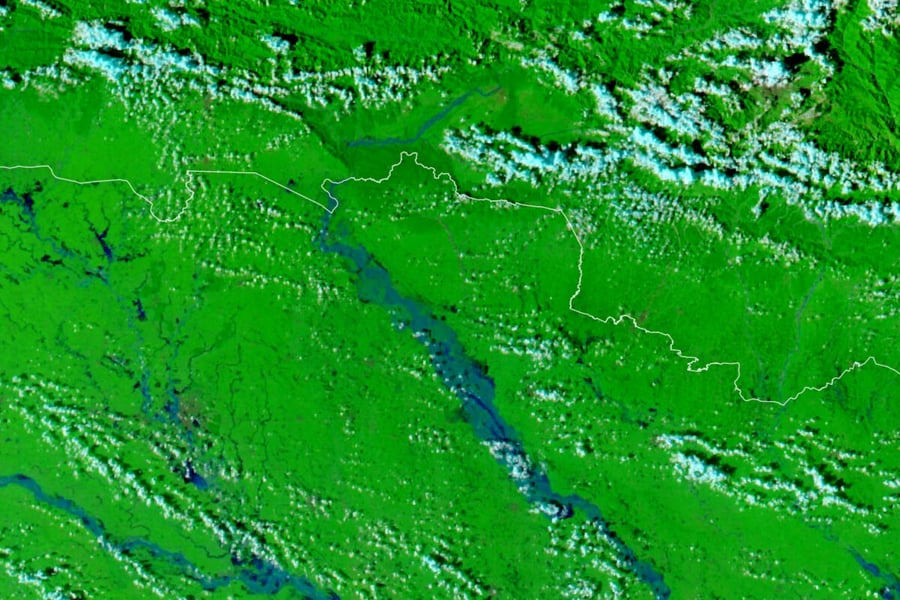 False-color satellite image of floodwater in blue along the Gandak River across the Nepal-India border, with green vegetation and clouds
