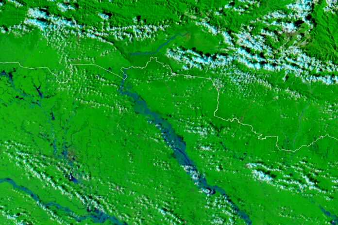 False-color satellite image of floodwater in blue along the Gandak River across the Nepal-India border, with green vegetation and clouds