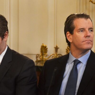 Gemini co-founders Cameron and Tyler Winklevoss seated side by side in a gilded room