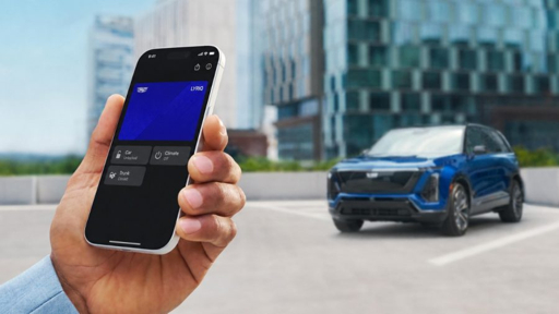 A hand holds a phone displaying a Cadillac digital key beside a blue SUV
