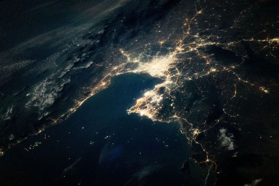 Night view from orbit of the Gulf of Thailand, with Bangkok's lights at the head of the bay and green dots of fishing boats on the dark water