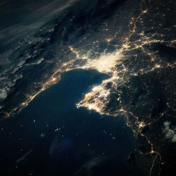 Night view from orbit of the Gulf of Thailand, with Bangkok's lights at the head of the bay and green dots of fishing boats on the dark water