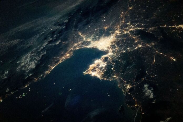 Night view from orbit of the Gulf of Thailand, with Bangkok's lights at the head of the bay and green dots of fishing boats on the dark water