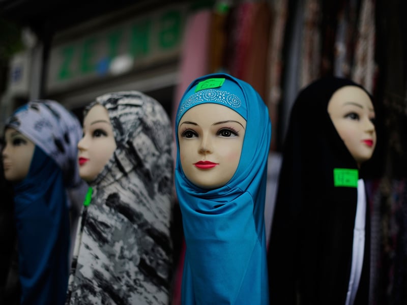 Hijabs in several colors displayed on mannequin heads outside a shop