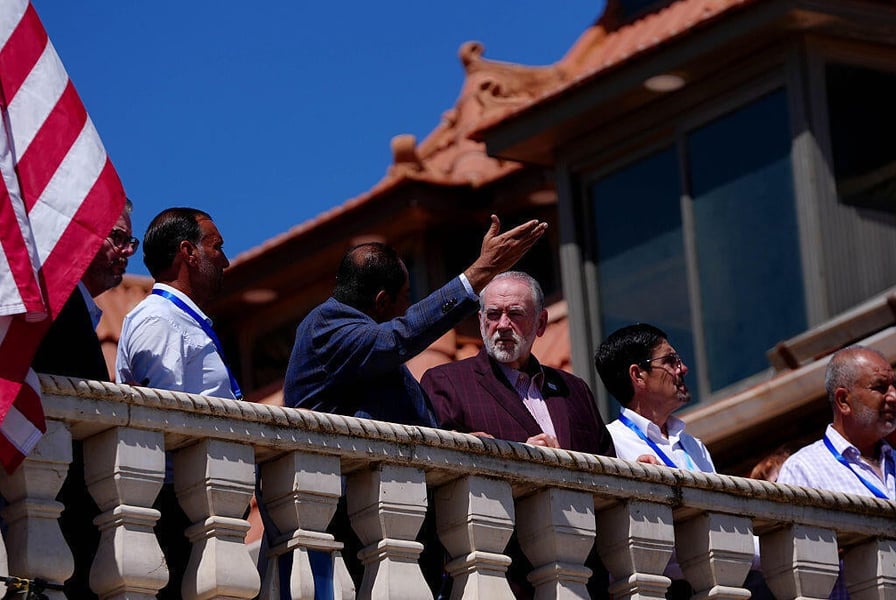 Mike Huckabee stands behind a stone balustrade with other men during a visit to Turmus Ayya in the West Bank
