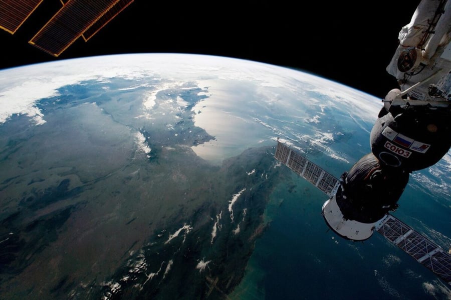 Orbital view of the Indochinese Peninsula with sunlight glinting off the Gulf of Thailand and southern Cambodia, with a Soyuz spacecraft in the foreground