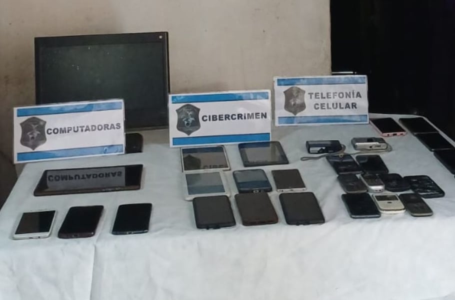 Computers, tablets and mobile phones laid out on a table under cybercrime signs after seizure by Argentine authorities
