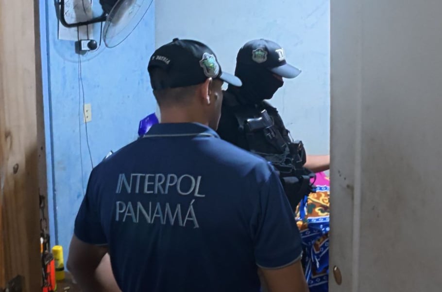 An INTERPOL Panama officer and a masked police officer inside a room during a search