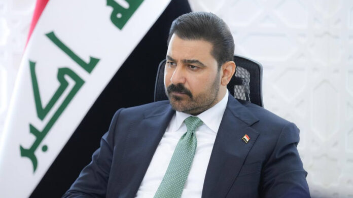 Iraqi Prime Minister Ali al-Zaidi seated in front of an Iraqi flag