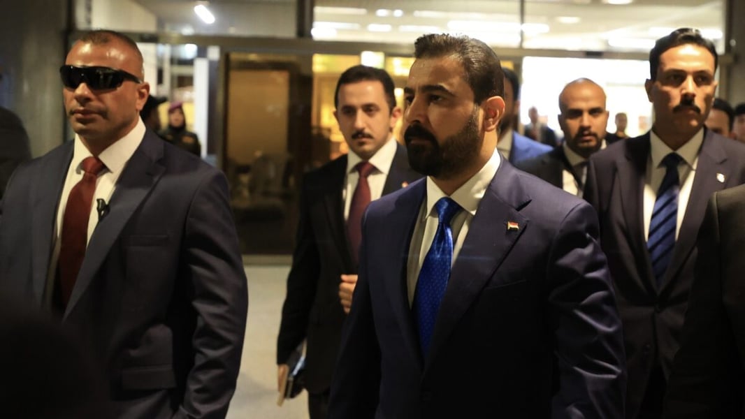 Ali al-Zaidi in a dark suit walking with aides and security officers in Baghdad
