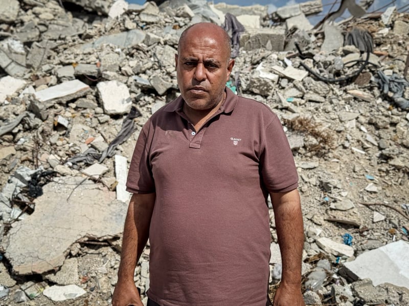 Ismail al-Barawi, a 52-year-old man from Jabalia, standing before a pile of rubble in Gaza