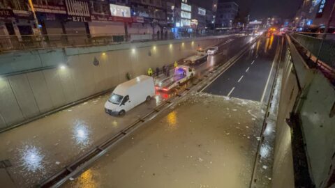 A white van stranded in floodwater on a sunken Istanbul roadway at night as tow trucks and responders gather