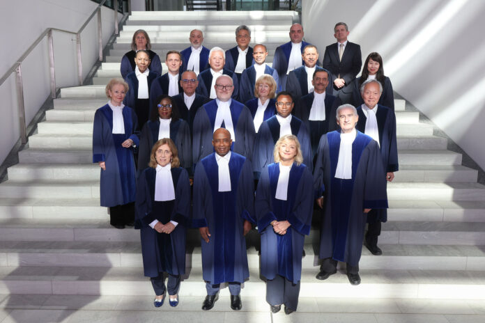 Judges of the International Tribunal for the Law of the Sea in blue robes posing on a white staircase in Hamburg