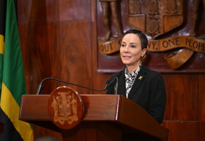 Foreign Minister Kamina Johnson Smith answers questions at a lectern bearing the Jamaican coat of arms