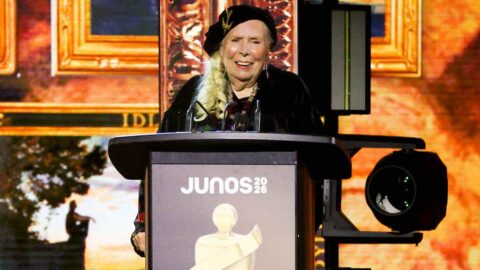 Joni Mitchell in a beret smiling at a podium at the 2026 Juno Awards