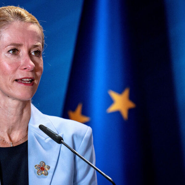 EU foreign policy chief Kaja Kallas speaking at a lectern in front of an EU flag