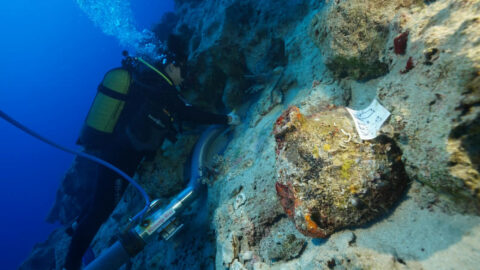 A diver beside an amphora on a rocky seabed at the shipwreck site near Kekova Island