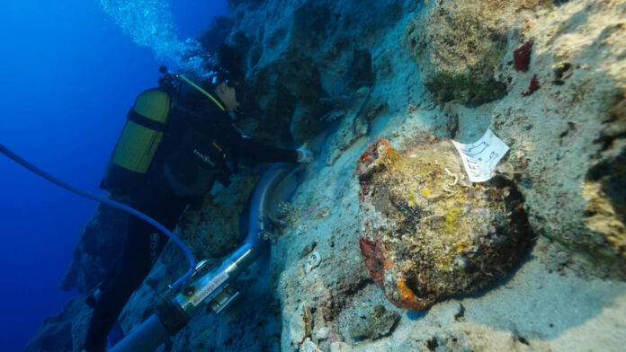 A diver beside an amphora on a rocky seabed at the shipwreck site near Kekova Island