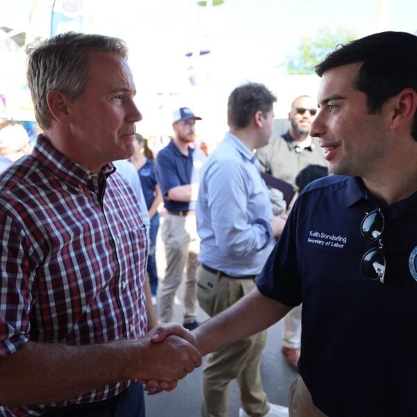 Labor Secretary Keith Sonderling in a Department of Labor polo shakes hands with a man in a plaid shirt at the Fulton County Fair in northwest Ohio