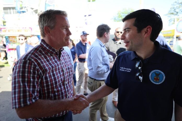 Labor Secretary Keith Sonderling in a Department of Labor polo shakes hands with a man in a plaid shirt at the Fulton County Fair in northwest Ohio