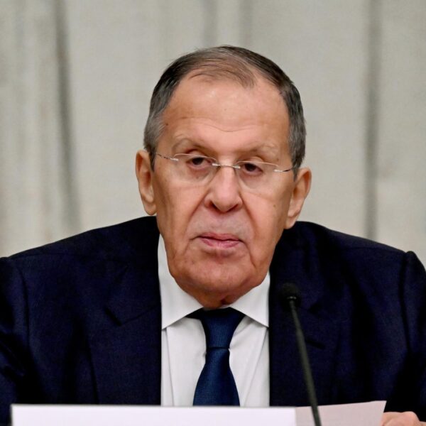 Russian Foreign Minister Sergey Lavrov seated at a table with a microphone and papers in front of him